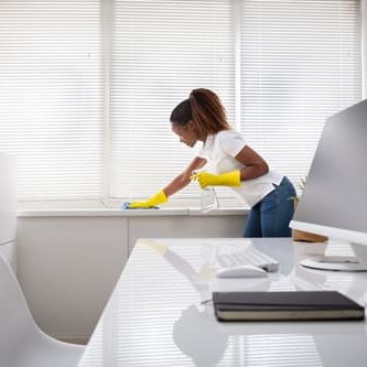 Woman Cleaning The Window Sill In Office